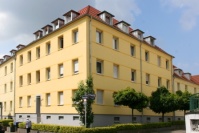 Eckansicht gelbes Wohnhaus mit vier Etagen.