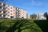 Mehrere Häuser mit 4 Etagen, Flachdächern. Vorne Wiese.