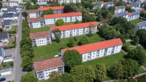 sanierte Wohnhäuser mit 3 Etagen, Satteldächern, helle Fassaden. Rundum Grünflächen mit Bäumen