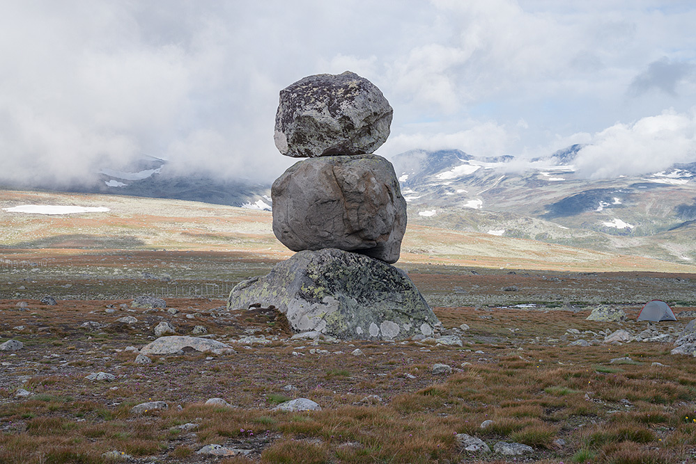 Three rocks on top of each other in a rural setting