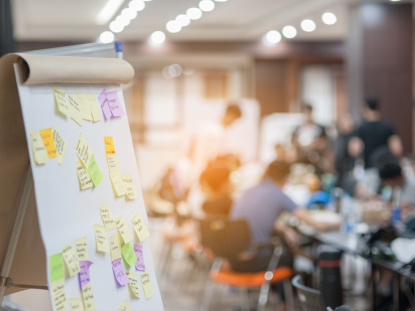 Workshop Flipchart im Vordergrund, Menschen im Hintergrund