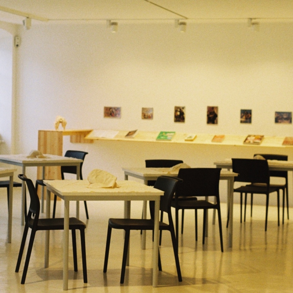 Tische und Stühle mit verhüllten Gegenständen stehen im Ausstellungsraum
