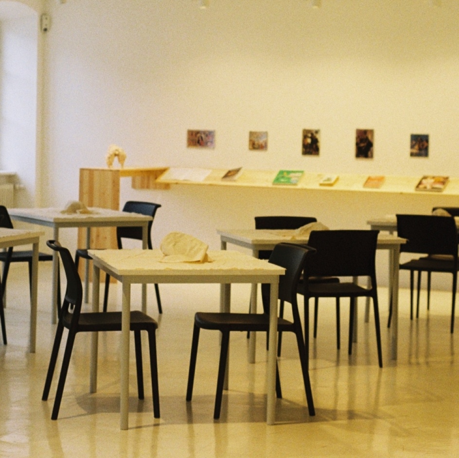 Tische und Stühle mit verhüllten Gegenständen stehen im Ausstellungsraum