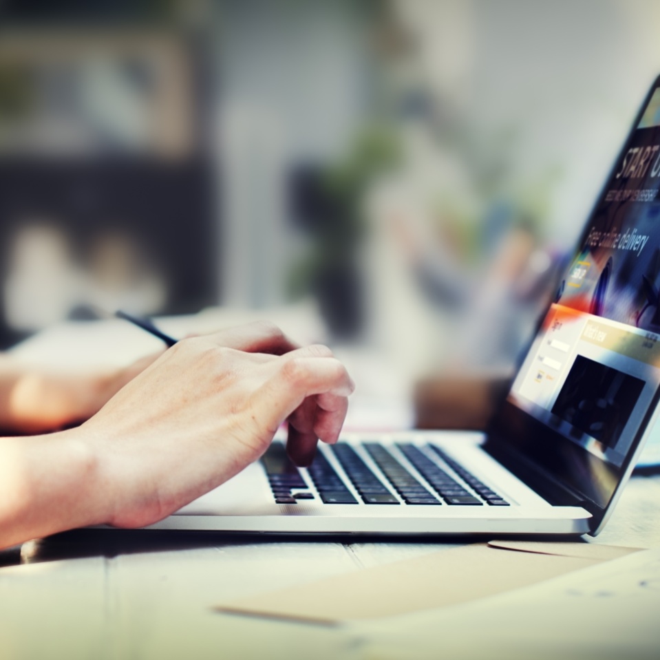 Die Hände einer Person liegen auf den Tasten eines Laptops