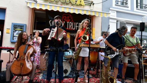 Savoy Truffle vor Tante Anna Eine Band mit acht MusikerInnen – unter anderem Cello, Akkordeon, Saxophon, Gitarre, Bass und Schlagzeug – vor der Kneipe Tante Anna