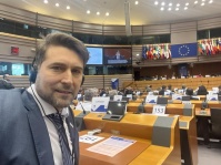 Eine Person sitzt vor einem Pult und trägt Kopfhörer. 