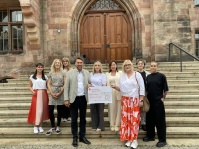 Eine Gruppe von Frauen übergibt einen Spendenscheck an einen Amtsträger