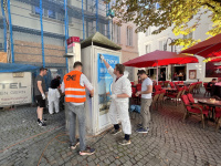 Menschen in Warnwesten reinigen einen Verteilerkasten 