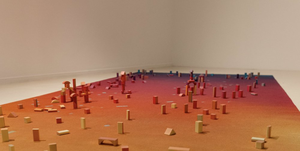 PLAYGROUND von Vanessa Husson & Geoffrey Blan Zu sehen ist ein bunter Teppich mit Holzblöcken, es handelt sich um das Kunstwerk PLAYGROUND von Vanessa Husson & Geoffrey Blan.