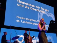 Eine Band auf einer Bühne, dahinter eine Leinwand mit blauem Motiv