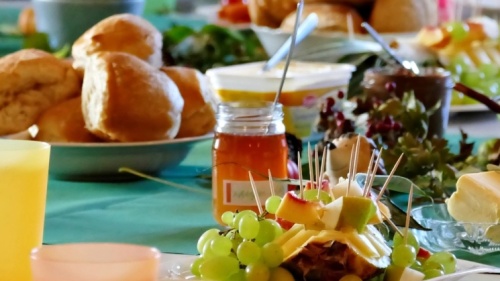 Frühstück Frühstückstafel mit bunten Gedecken, Brötchen und Butter