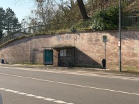Straße mit Buswartehäuschen vor einer Mauer